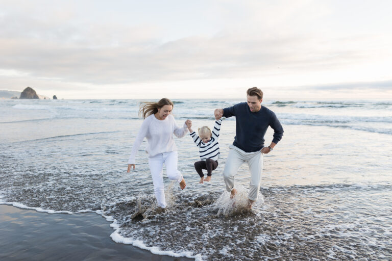 family splashing in the ocean during family photos in cannon beach
