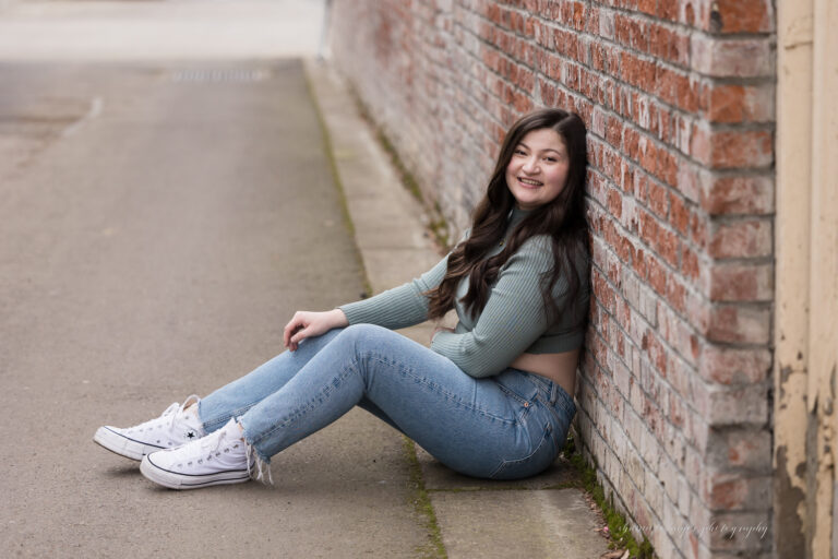 girl senior photo by brick wall